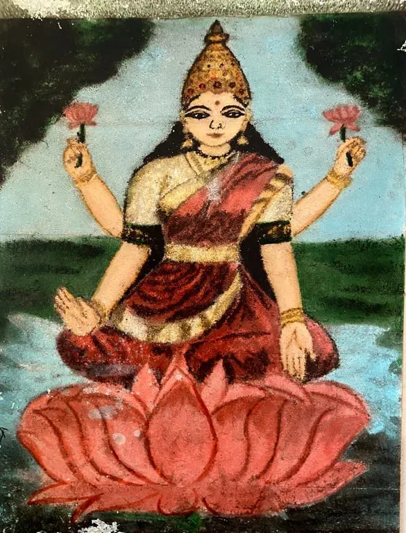 Coloured rangoli of Goddess Lakshmi seated on a pink lotus holding lotuses, on a blue ground