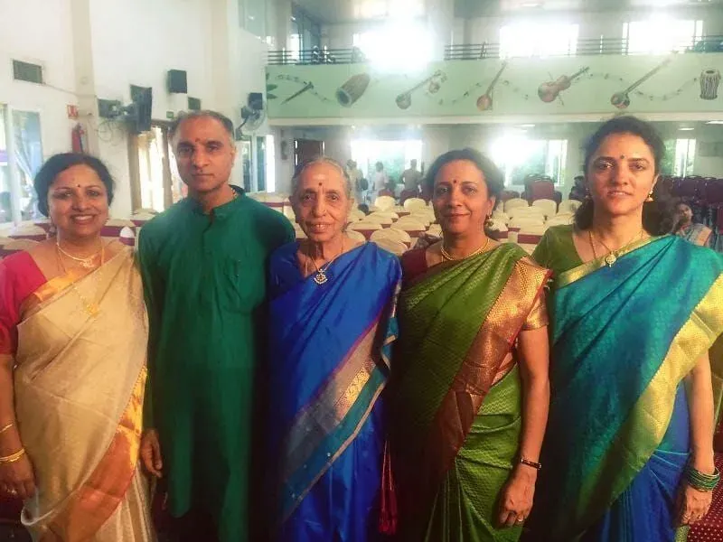 Lakshmi Santhanam in a blue silk sari with four family members in silk saris and a green kurta, in a hall