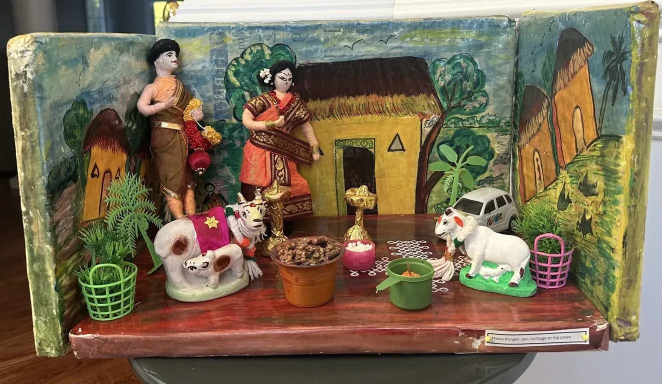 Painted box scene for Mattu Pongal: a village house, two decorated cows, a calf and villagers with pots against a hand-painted backdrop