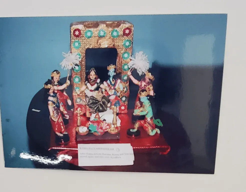 Doll scene of a wedding beneath an arched mandapam with attendants, with a caption card, from the Ramayana series