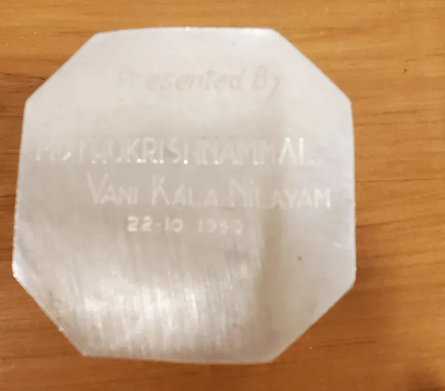An octagonal white stone plaque engraved Presented by Muthukrishnammal, Vani Kala Nilayam, 22-10-1959