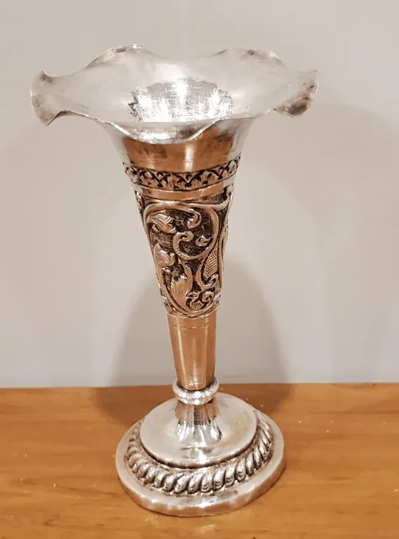 A fluted silver vase engraved with vines, on a wooden table, a gift from her students