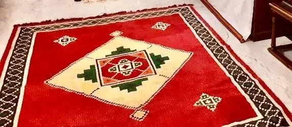 A red mat with a diamond kolam design worked in white, green and yellow