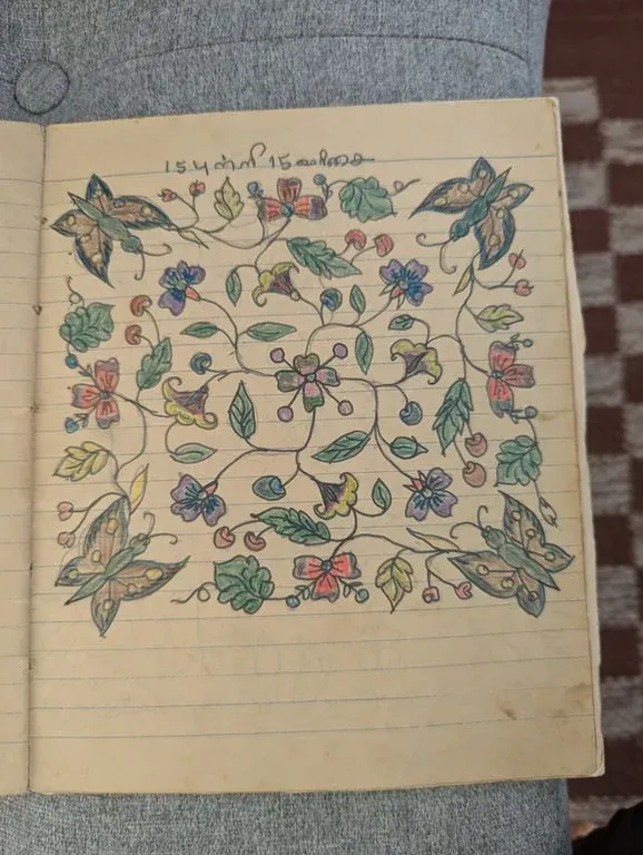 Coloured kolam of flowers and butterflies filling a square, on a ruled page