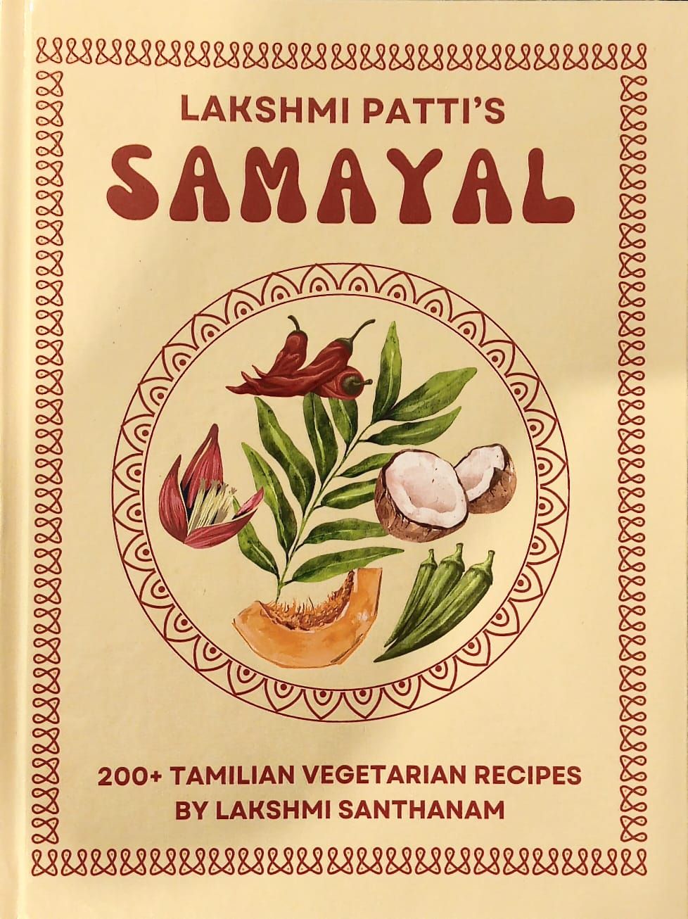 Front cover: cream ground with a red kolam border and a painted circle of red chillies, a curry leaf sprig, split coconut, pumpkin, okra and a banana flower