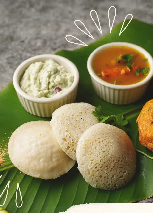 Idlis with coconut and tomato chutney and sambar on a banana leaf
