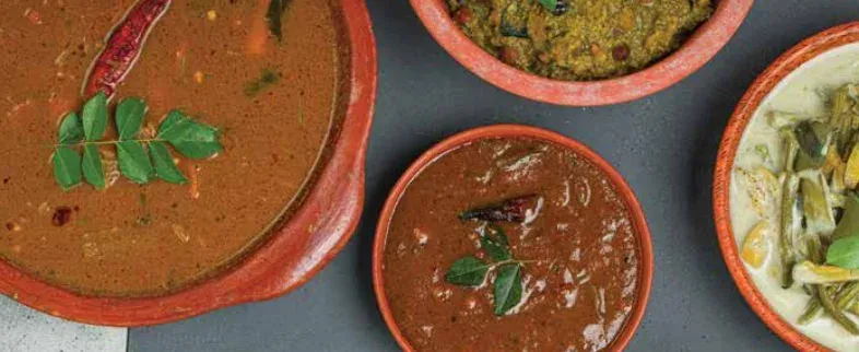 Bowls of kuzhambu and a coconut-based curry