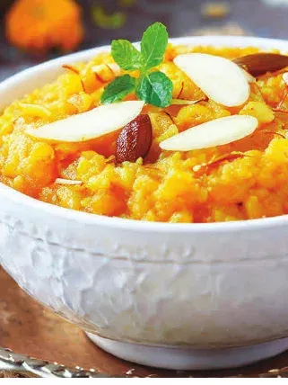 Kesari garnished with almond slivers, in a white bowl