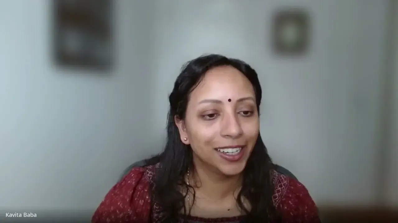 Kavita smiling on a video call, in a red top